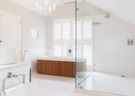 Люстра над мокрой ванной в современной ванной комнате — стоковое фото