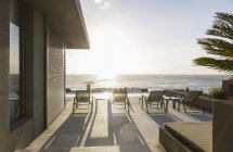 Гостиные стулья на солнечном роскошном патио с видом на океан — стоковое фото