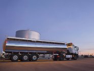 Молочний танкер з нержавіючої сталі біля вежі для зберігання силосу — стокове фото