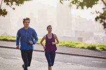Runner couple running on sunny urban city street — Stock Photo