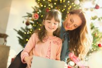 Мати дивиться дочку відкриває різдвяний подарунок — стокове фото