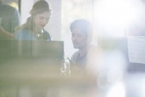 Kreative Geschäftsleute mit Kopfhörern am Computer im sonnigen Büro — Stockfoto