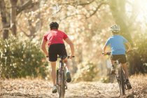 Father and son mountain biking on path in woods — Stock Photo