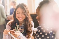Freundinnen texten mit Mobiltelefonen im Café — Stockfoto
