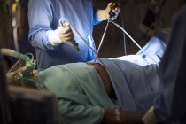 Chirurgien tenant des outils médicaux et effectuant une chirurgie laparoscopique en salle d'opération — Photo de stock