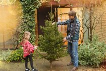 Father and daughter with Christmas tree outside house — Stock Photo