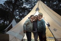 Niños abrazándose por tipi en el camping - foto de stock