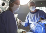Médicos masculinos e femininos realizando cirurgia laparoscópica no centro cirúrgico — Fotografia de Stock