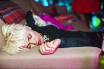 Молода жінка спить на дивані на вечірці — стокове фото