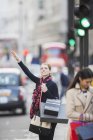 Woman hailing taxi on city street — Stock Photo