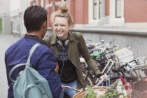 Молодой человек и женщина с велосипедом смеются на городской улице — стоковое фото