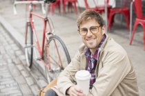 Человек, пьющий кофе на городской улице — стоковое фото