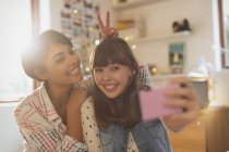 Playful young women taking selfie with camera phone — Stock Photo