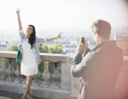 Mann fotografiert Freundin mit Stadt im Hintergrund — Stockfoto