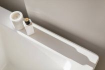 Vela e garrafa fundição sombra na borda da banheira branca — Fotografia de Stock