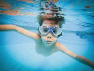 Porträt eines Jungen, der in Schwimmbad unter Wasser schwimmt — Stockfoto