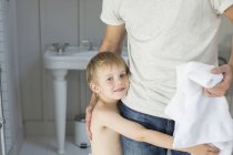 Niño abrazando padre en cuarto de baño - foto de stock