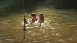 Casal jovem nadando em lago ensolarado — Fotografia de Stock