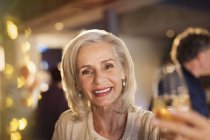 Porträt lächelnde Seniorin prostet Weißweinglas an Bar zu — Stockfoto