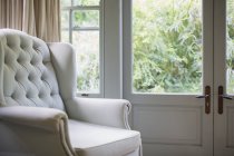 Tufted wingback chair near window — Stock Photo