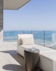 Chaise lounge e vidro de água na varanda de luxo ensolarada com vista para o mar — Fotografia de Stock