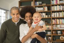Familie lächelt gemeinsam im heimischen Wohnzimmer — Stockfoto
