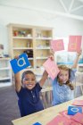 Estudantes segurando cartas em sala de aula — Fotografia de Stock