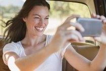Жінка їде в машині фотографується з мобільним телефоном — стокове фото