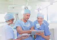 Хірурги і медсестра використання буфера обміну і цифровий планшетний в операційний зал — стокове фото