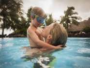 Mãe e filho abraçando na piscina — Fotografia de Stock