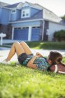 Дівчина лежить на футболі в траві зовні будинку — стокове фото