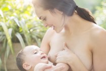 Mother breast-feeding baby boy outdoors — Stock Photo