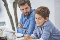 Father and son eating lunch at patio table — Stock Photo