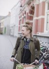 Lächelnde junge Frau mit Kopfhörern auf dem Fahrrad auf der Stadtstraße — Stockfoto