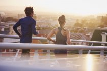 Runner couple running on footbridge with city view — Stock Photo