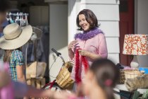 Woman trying on feather boa at yard sale — Stock Photo