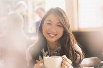 Portrait smiling Chinese woman drinking cappuccino in cafe — Stock Photo