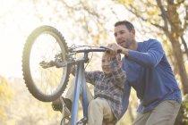 Pai ensinando filho wheelie na bicicleta — Fotografia de Stock