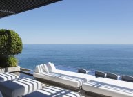 Sofas and infinity pool overlooking ocean — Stock Photo