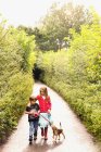 Niño y niña hermano y hermana perrito paseante con correa en el camino del parque arbolado - foto de stock