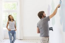 Homem parede de pintura com namorada observando — Fotografia de Stock