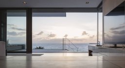 Home vetrina soggiorno e patio con tranquilla vista sull'oceano tramonto — Foto stock