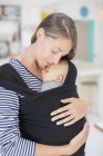 Gelassene Mutter hält Baby im Tragetuch — Stockfoto