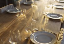 Sunny reflection on placesettings on wood dining table — Stock Photo