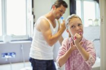 Father and daughter brushing teeth in bathroom — Stock Photo