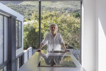 Portrait femme mature confiante debout dans la maison moderne vitrine cuisine intérieure — Photo de stock