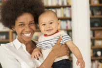 Mother holding baby boy in living room at home — Stock Photo