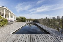 Tranquil home showcase swimming pool surrounded by wooden deck — Stock Photo