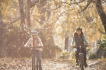 Mother and daughter bike riding on path in woods — Stock Photo