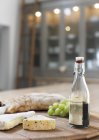 Fromage, vinaigre balsamique, raisins et baguette sur planche de bois — Photo de stock